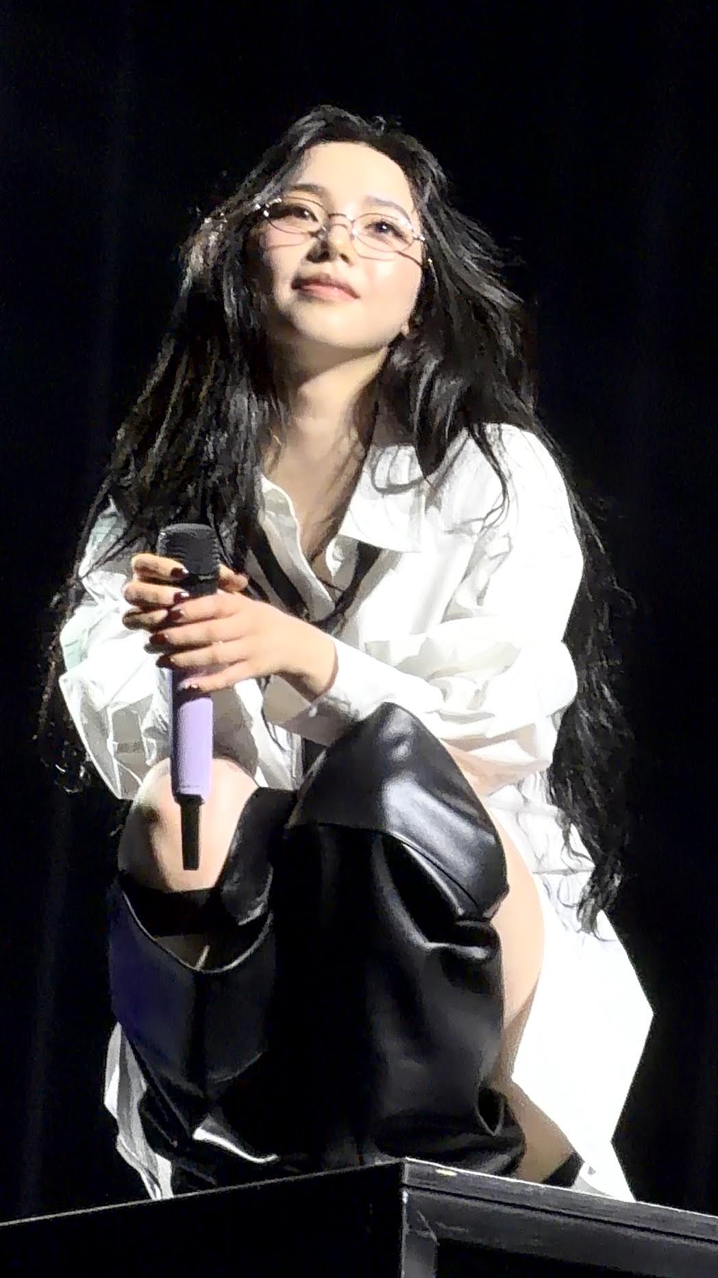 An aespa member holding a microphone at the extended stage
